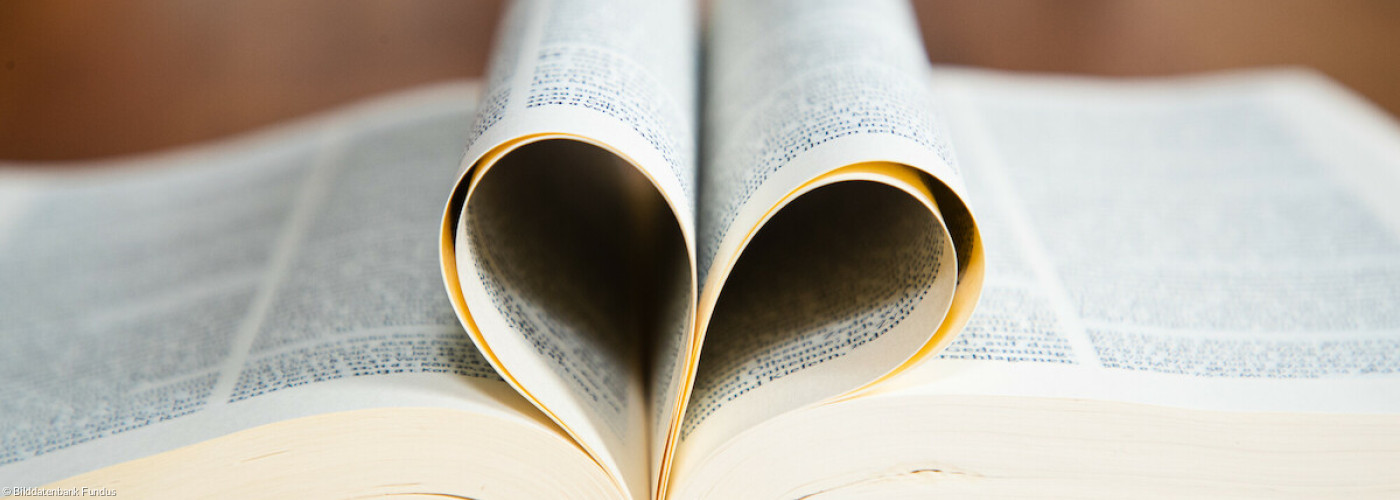 Aufgeschlagene Bibel - Seiten zum Herz gefaltet