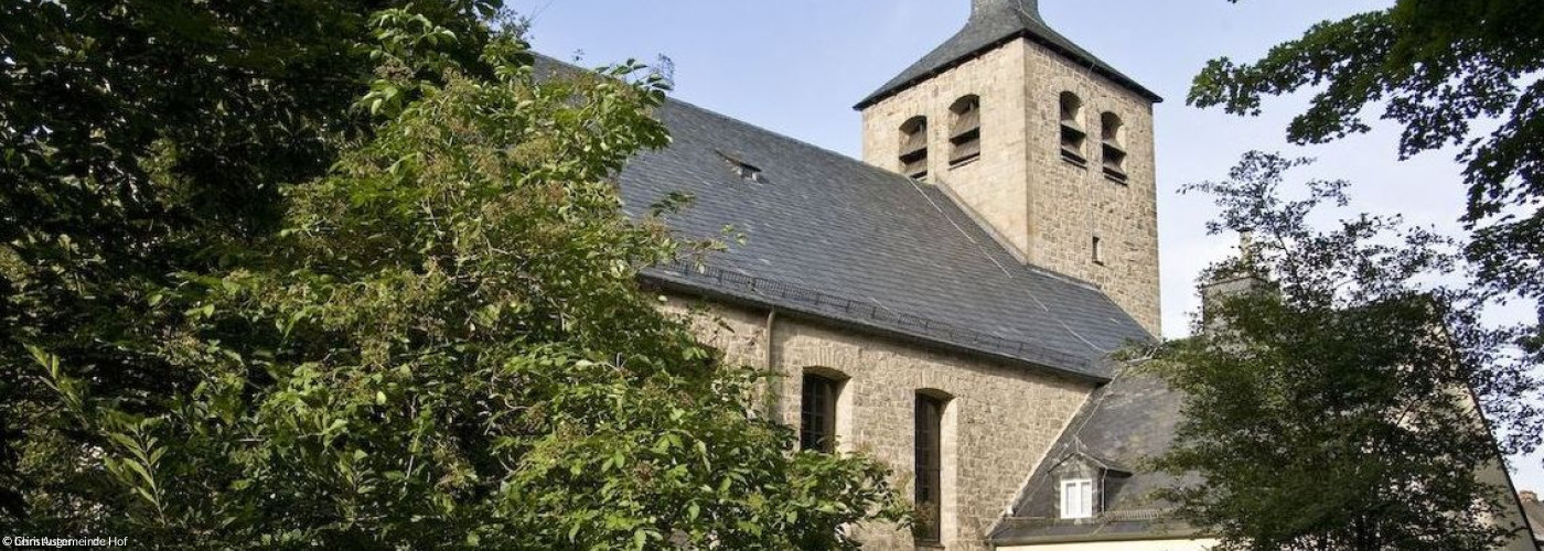 Christuskirche vor Bäumen, grauer Backsteinbau mit Turm