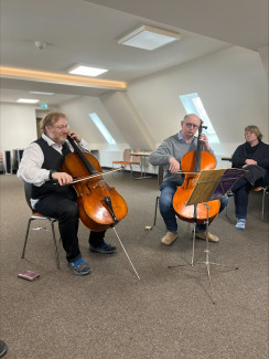 Zwei Männer mittleren Alters spielen Cello