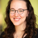 Junge Frau mit dunklen Locken lächelt in die Kamera